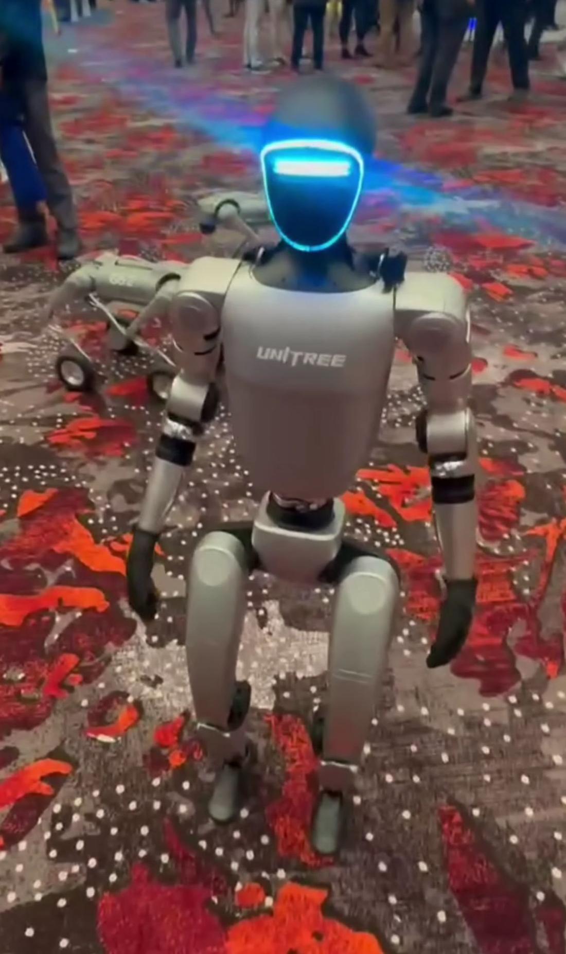 Unitree G1 humanoid at an expo. Where: Expo (Commons: 'UAV expo 2024', 18 Nov 2024). The photo is a low-quality video-style frame from an exhibition.