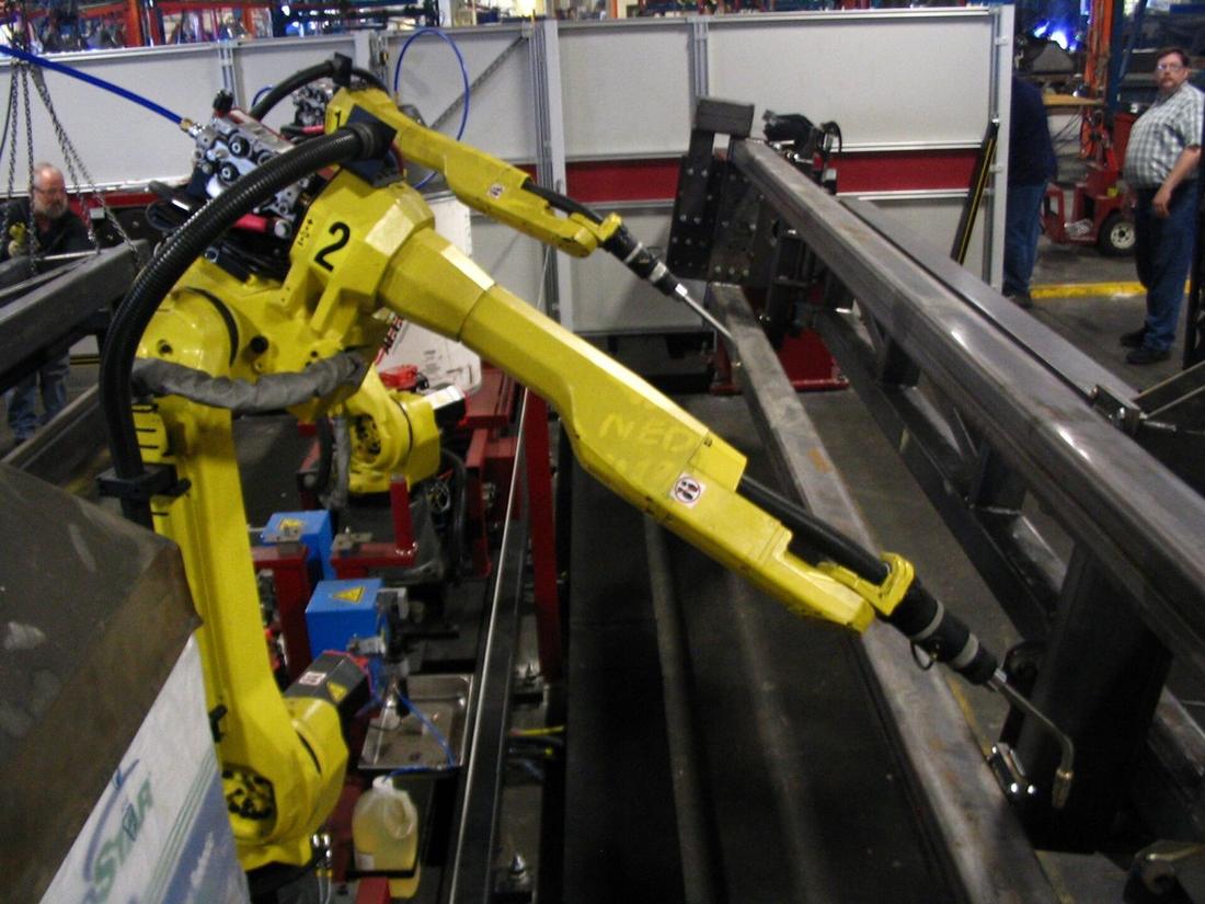 FANUC arc welding robots on a steel frame.